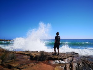 Boy looking at rough see on sunny day