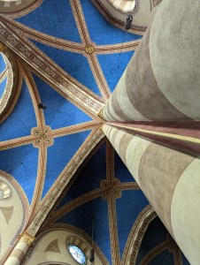 View looking up the side of a pillar at an ancient church painted ceiling