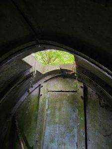 Picture of a building made of concrete panels with an open square of roof with a hint of green woodlands above